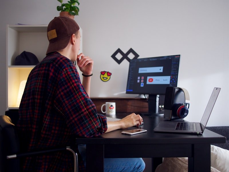 Programador escrevendo código em dois monitores