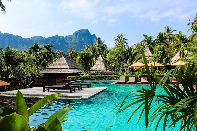 Resort tropical com piscina, bangalôs e montanhas ao fundo